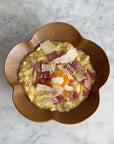 Elegant UME bowl with creamy risotto, topped with shaved cheese and ham, enhancing any table setting.