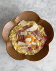 Elegant UME bowl with creamy risotto, topped with shaved cheese and ham, enhancing any table setting.