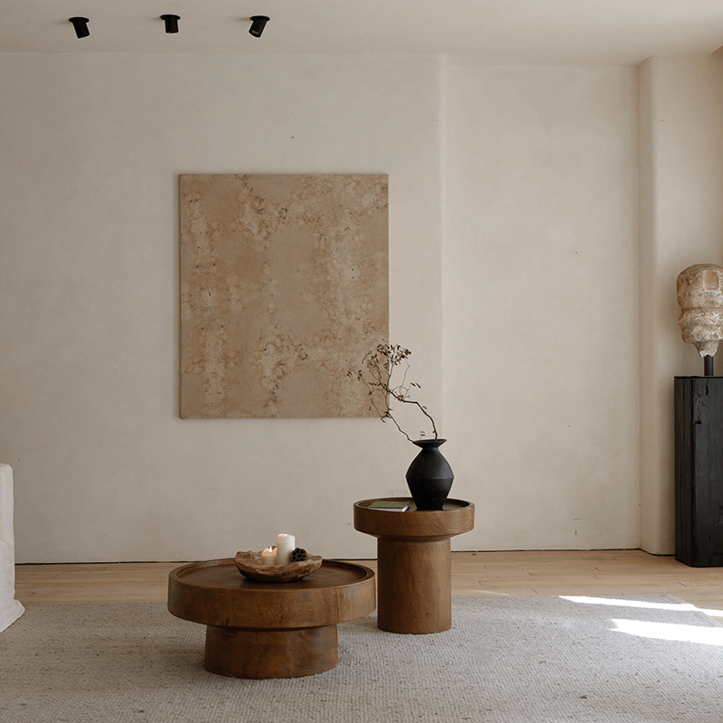 Elegant living room with a wooden coffee table set, featuring natural log textures and a minimalist design against a light wall background.
