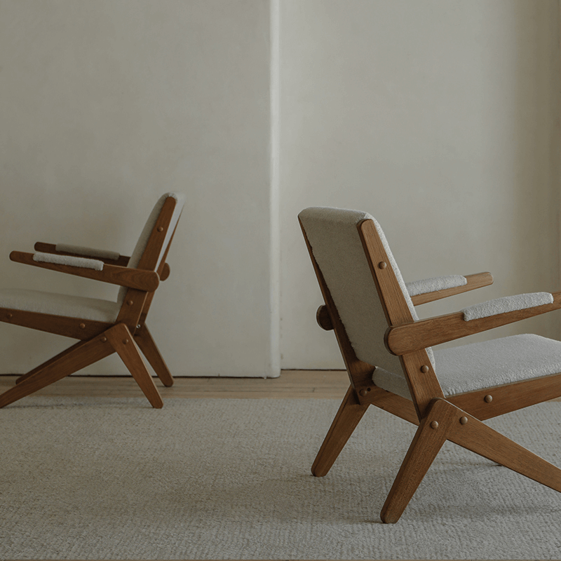 Two Scissors Chairs made of imported teak wood with S-shaped frames and armrests, showcasing a minimalist lounge design in a neutral room.