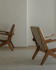 Two Scissors Chairs made of imported teak wood with S-shaped frames and armrests, showcasing a minimalist lounge design in a neutral room.