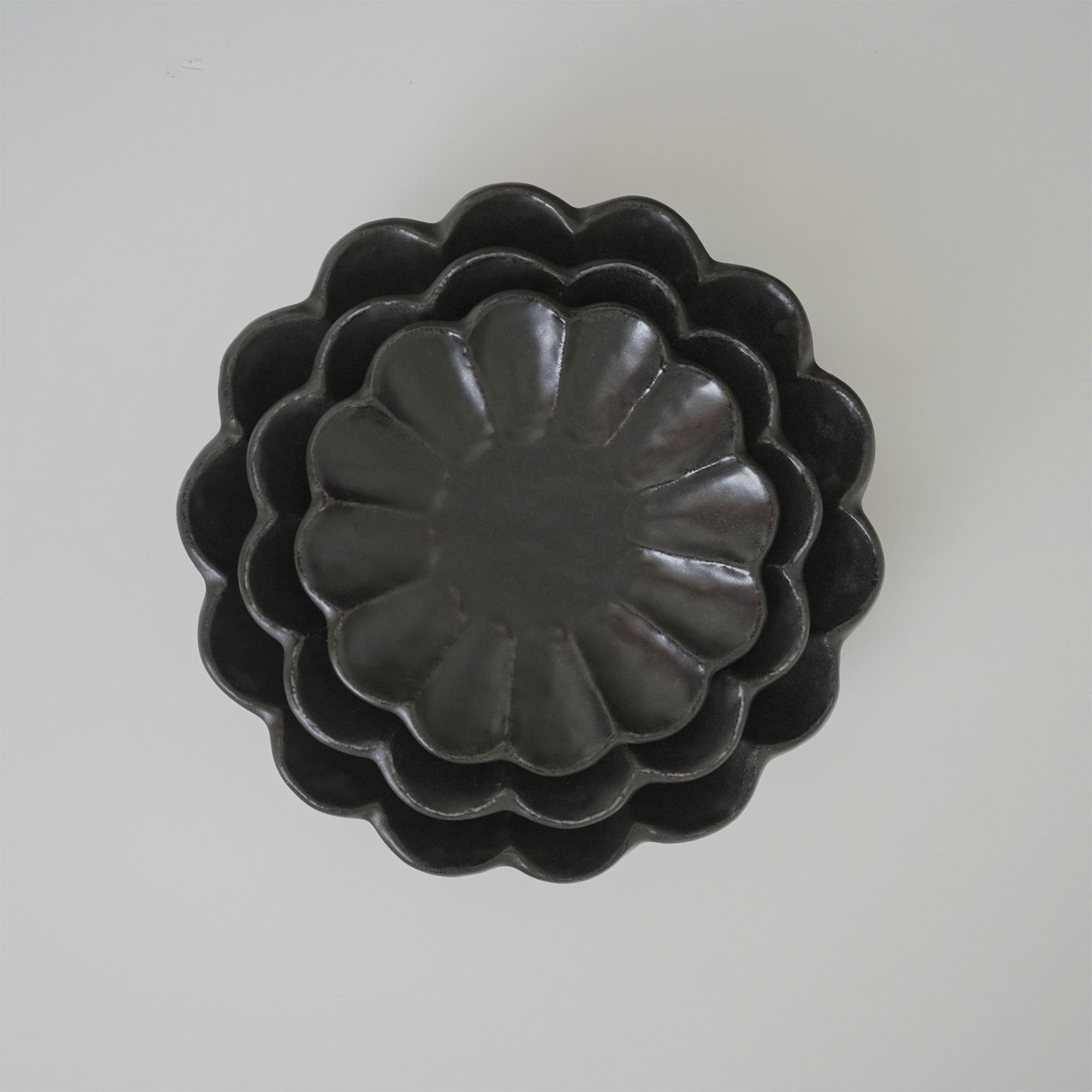Stacked black Rinka plates showcasing elegant scalloped design, handcrafted from porcelain by Kaneko Kohyo, Japan.