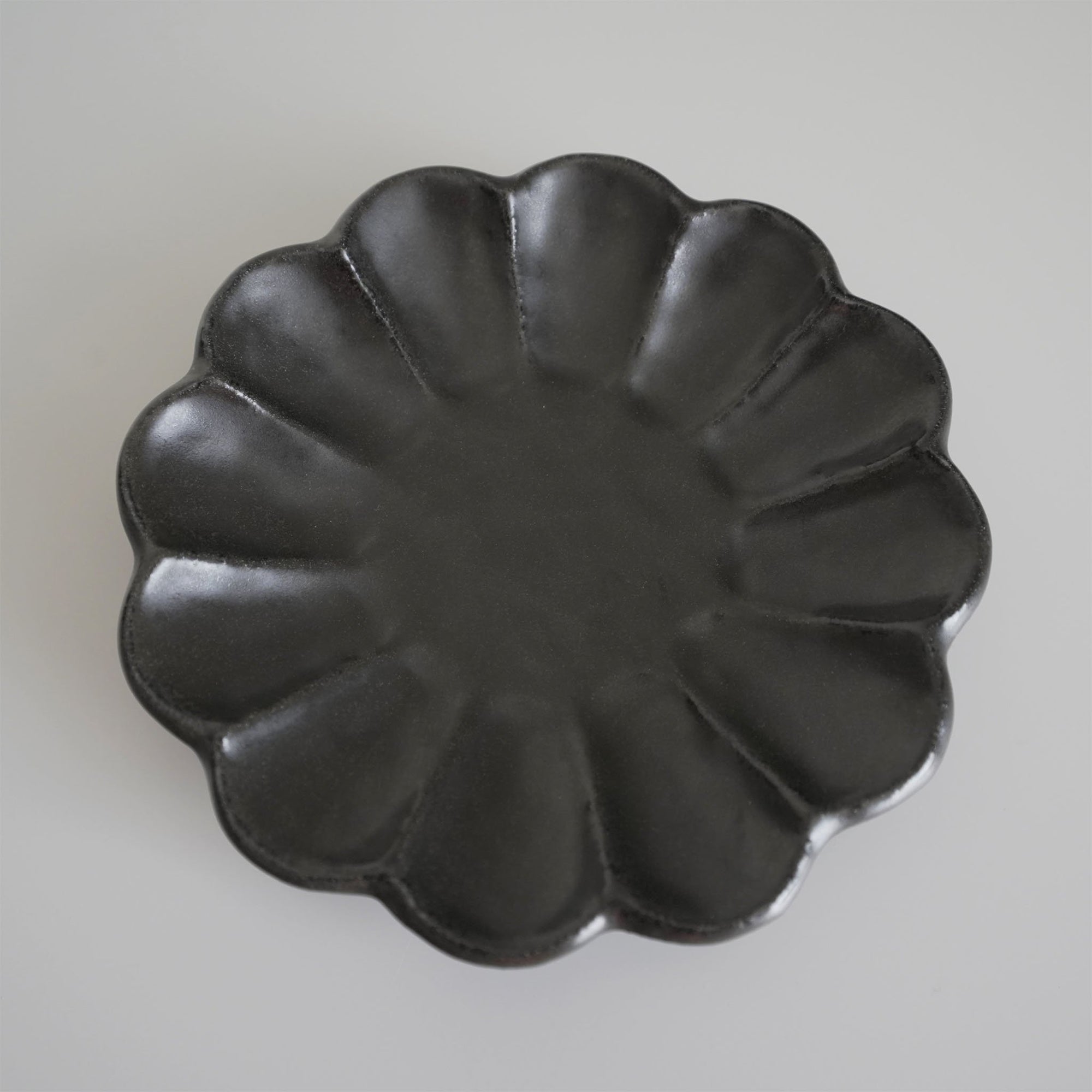 Elegant black Rinka Plate 21cm crafted in porcelain, featuring a unique flower-like design, part of Kaneko Kohyo's Japanese collection.