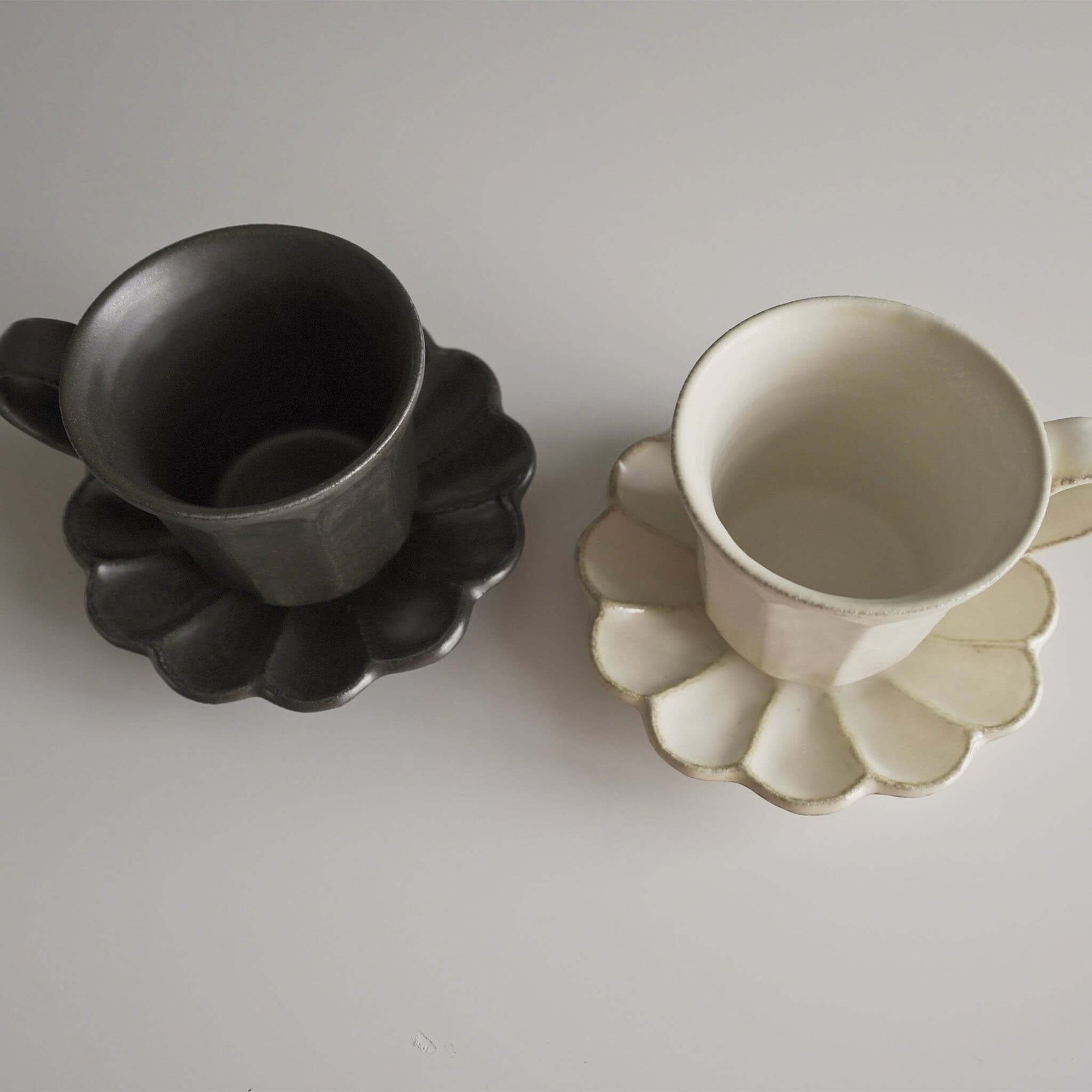 Rinka Mug & Plate Set in black and white porcelain, handmade in Japan, featuring unique glaze with flower-shaped plate design.