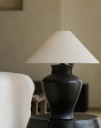 Short Neck Table Lamp with clay base and linen shade on a side table, offering warm, adjustable light for cozy home decor ambiance.
