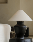 Short Neck Table Lamp with clay base and linen shade on a side table, offering warm, adjustable light for cozy home decor ambiance.