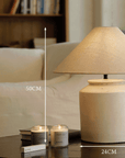 Folding Shoulder Table Lamp on a wooden table with candles, featuring a linen lampshade, clay base, and warm adjustable light.