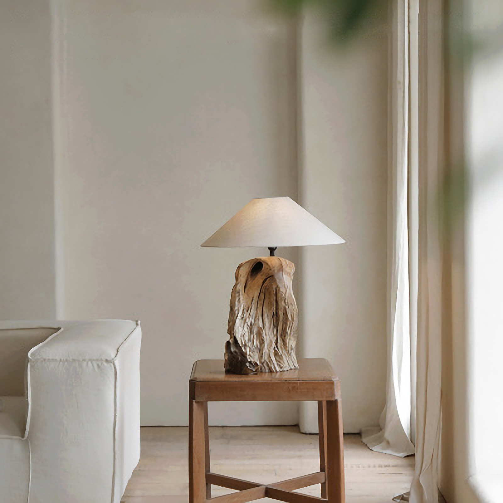 Rustic carved table lamp made from recycled wood on a wooden side table, enhancing a cozy living room atmosphere.