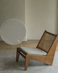 Kangaroo Chair with rattan and solid wood frame, featuring a Z-shaped design and close-up of fabric texture, on a wooden floor.