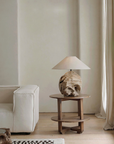 Stylish carved table lamp made from recycled wood with unique patterns, on a wooden side table in a cozy, minimalist living room setting.