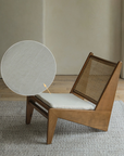 Kangaroo Chair with rattan and solid wood in Z shape design, featuring a textured cushion and curved backrest on wooden flooring.