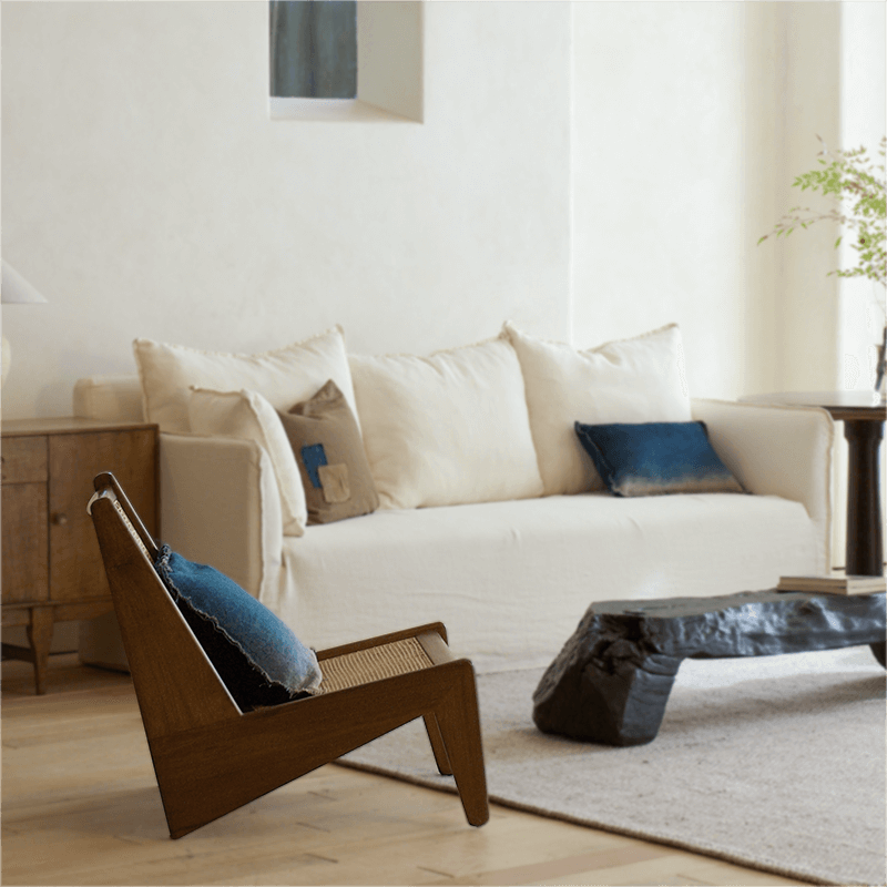 Modern living room featuring a Kangaroo Chair with rattan and wood design, placed beside a rustic coffee table and cream sofa.