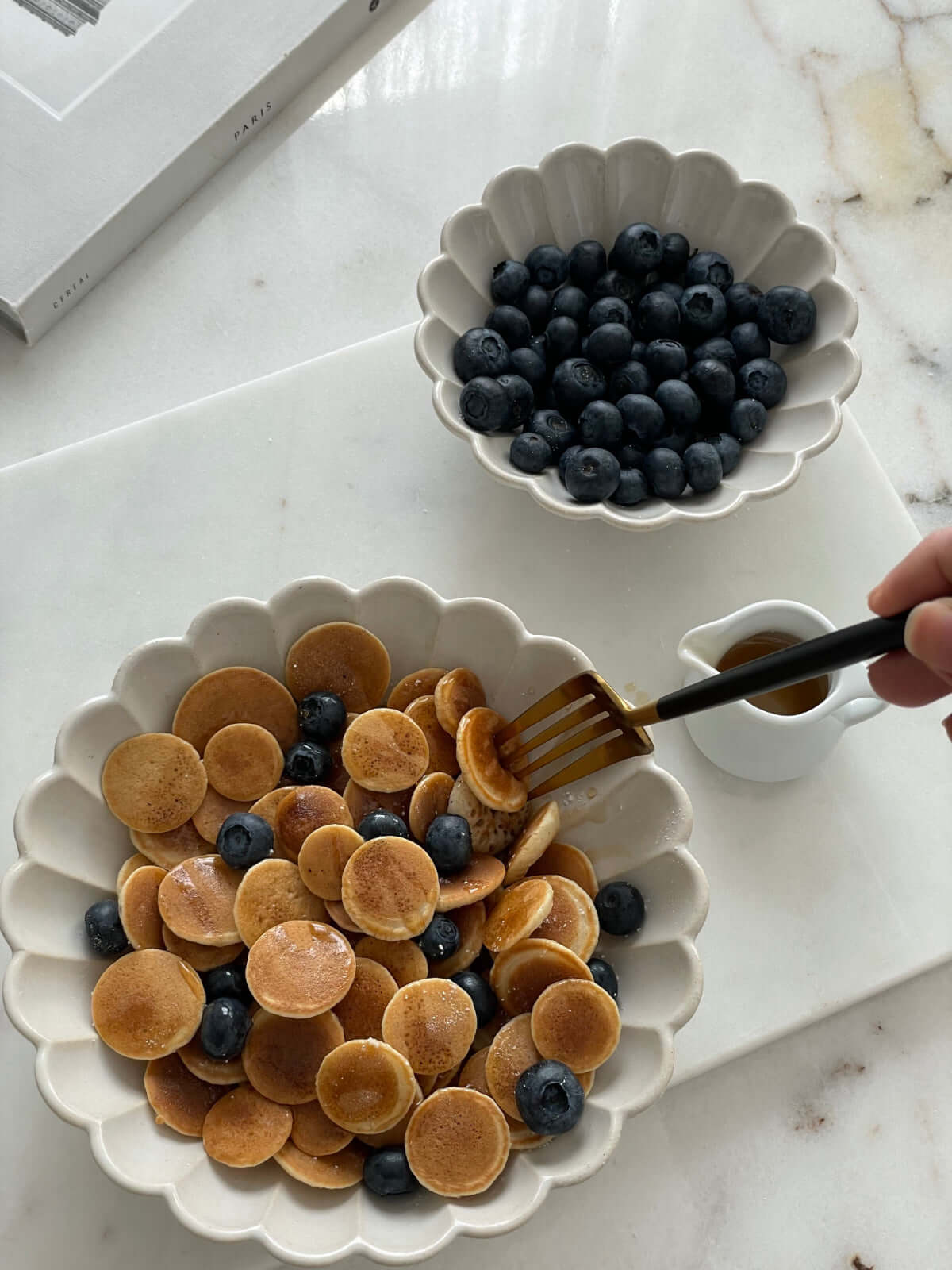 Elegant bowls filled with mini pancakes and blueberries, showcasing fine Japanese porcelain craftsmanship.