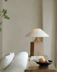 Old wood table lamp with linen lampshade on a wooden desk, creating a natural atmosphere in a cozy living room setting.