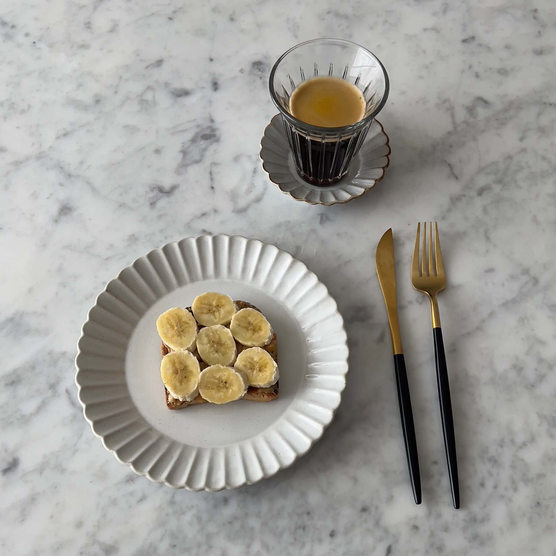 Elegant Marumitsu Barbarie plate with banana toast and cup of coffee on marble table setting