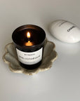 Byredo Bibliothèque candle lit, placed in a decorative bowl, alongside a Chanel La Crème Main hand cream.