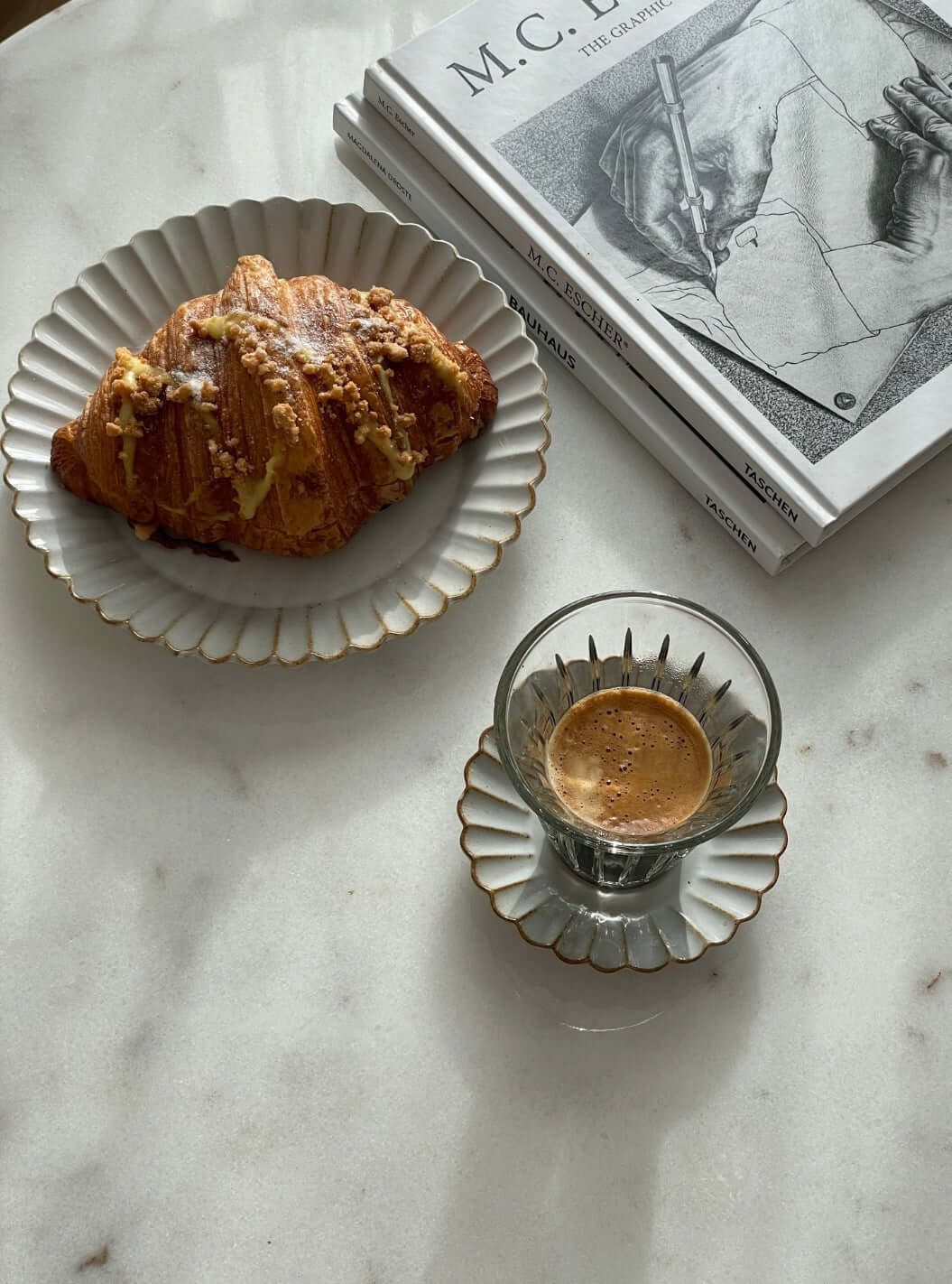 Marumitsu Barbarie plate with a croissant and espresso on a marble table, next to art books.