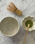 Ivory matcha bowl set with whisk, matcha powder, and bowl on a marble surface, ideal for Japanese tea ceremonies.