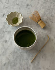 Ivory matcha bowl with whisk and matcha powder on marble surface, exemplifying Japanese matcha culture essentials.