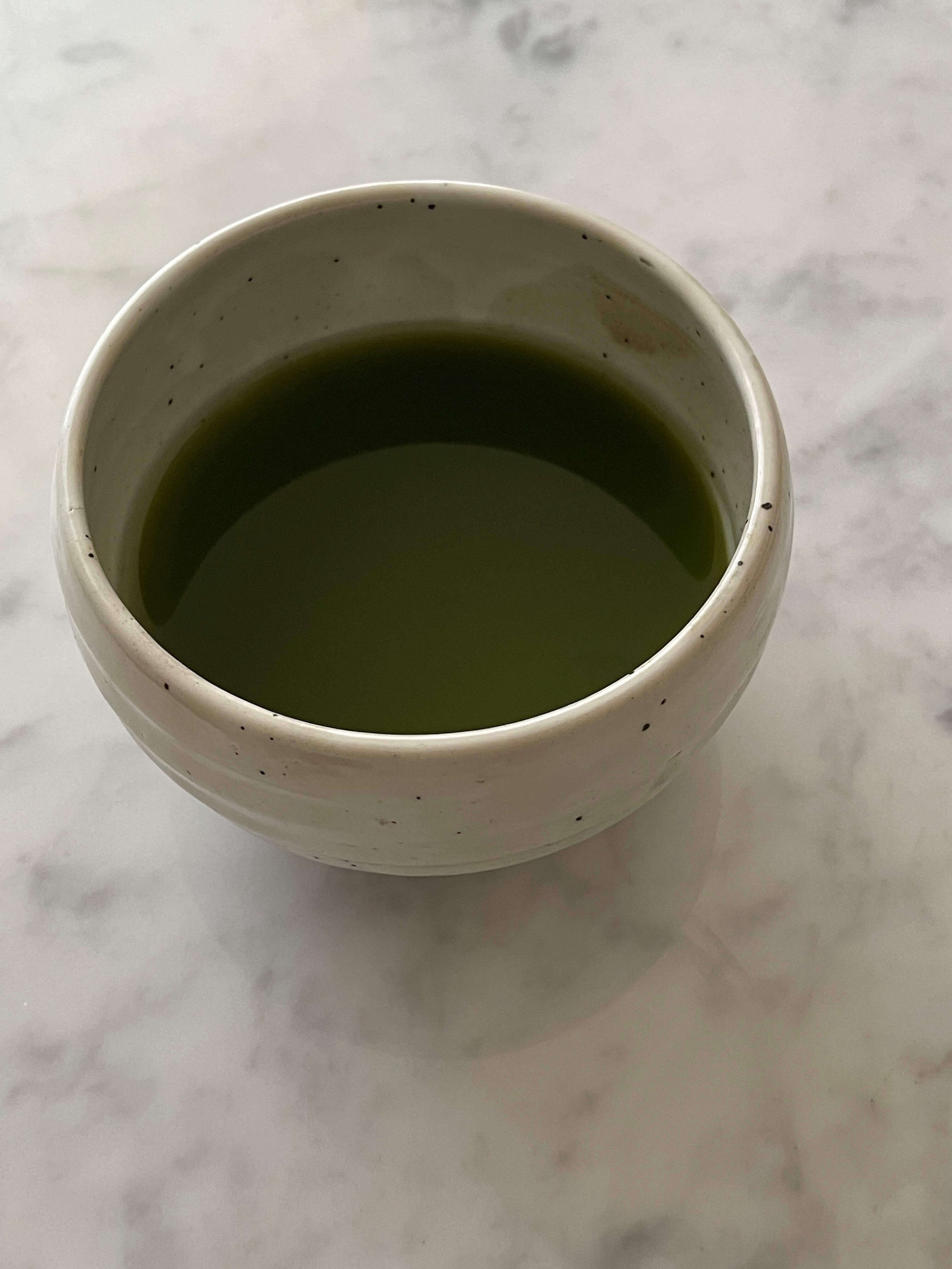 Ivory Matcha Bowl filled with green matcha tea, showcasing its rounded form and calm colors, made of Mino ware porcelain.