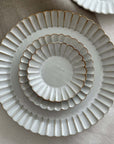 Elegant Marumitsu Barbarie plates with petal-like rim relief, stacked on a neutral fabric background. Perfect for sophisticated dining.