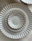 Elegant Marumitsu Barbarie plates with petal-like rim relief, stacked on a neutral fabric background. Perfect for sophisticated dining.