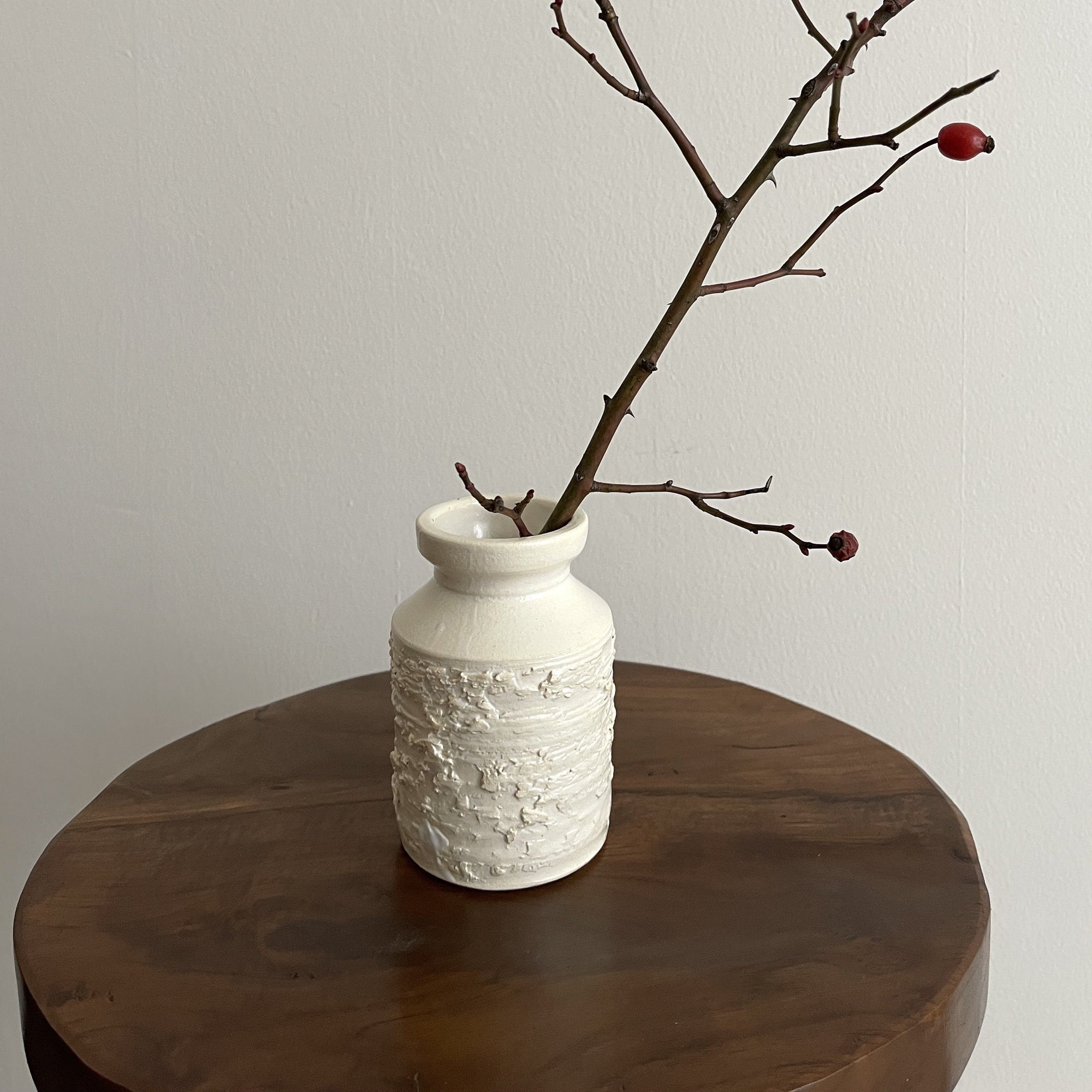 White vase by Yoshida Pottery with nature-inspired patterns on a wooden table, showcasing minimalist elegance and artisanal design.
