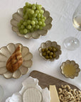 Elegant table setting with Rinka plates showcasing grapes, olives, bread, and wine on a white tablecloth.