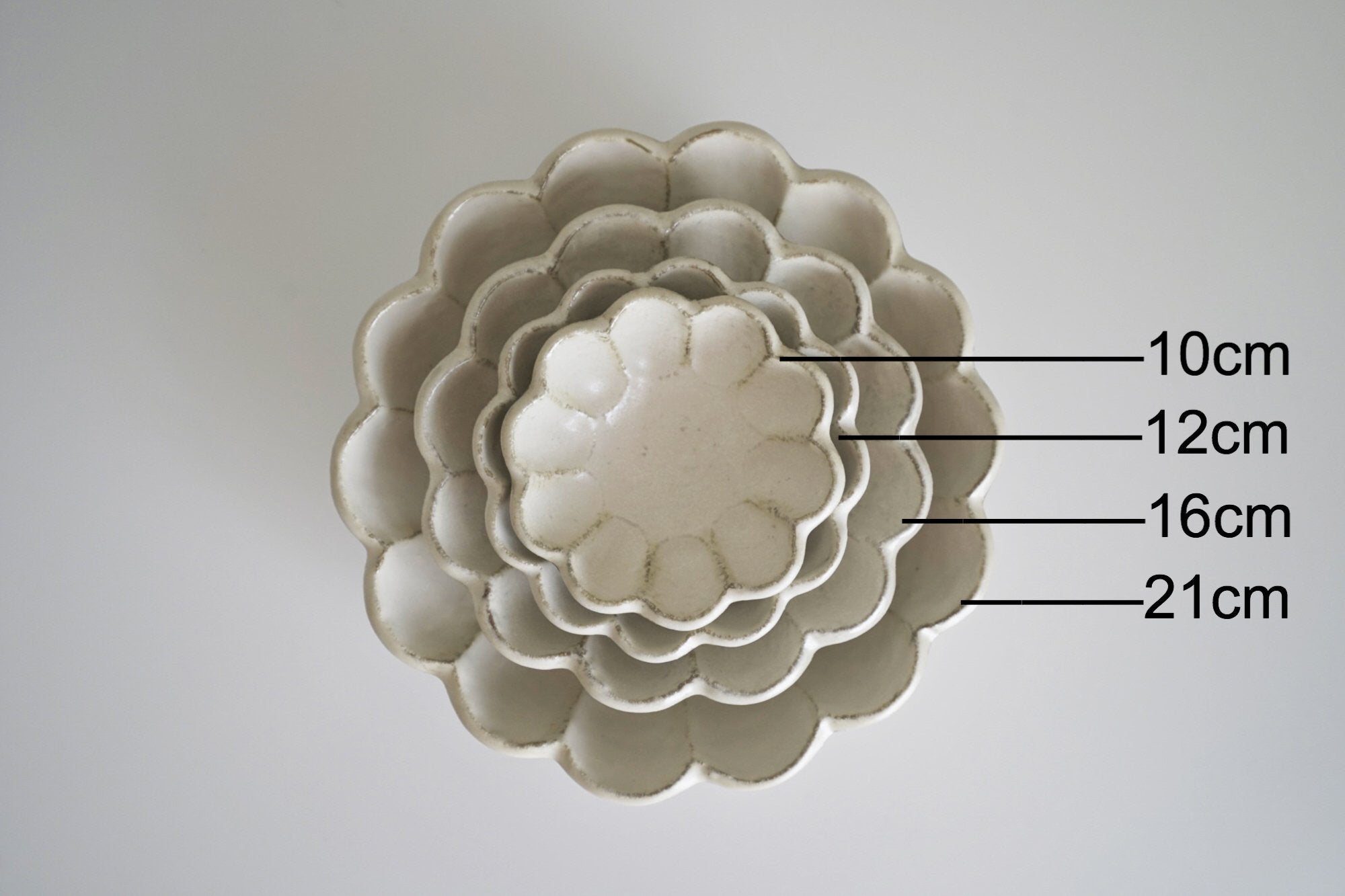 Stack of Rinka Bowls in flower shape, sizes 10cm, 12cm, 16cm, and 21cm, handmade porcelain by Kaneko Kohyo, enhancing table decor.