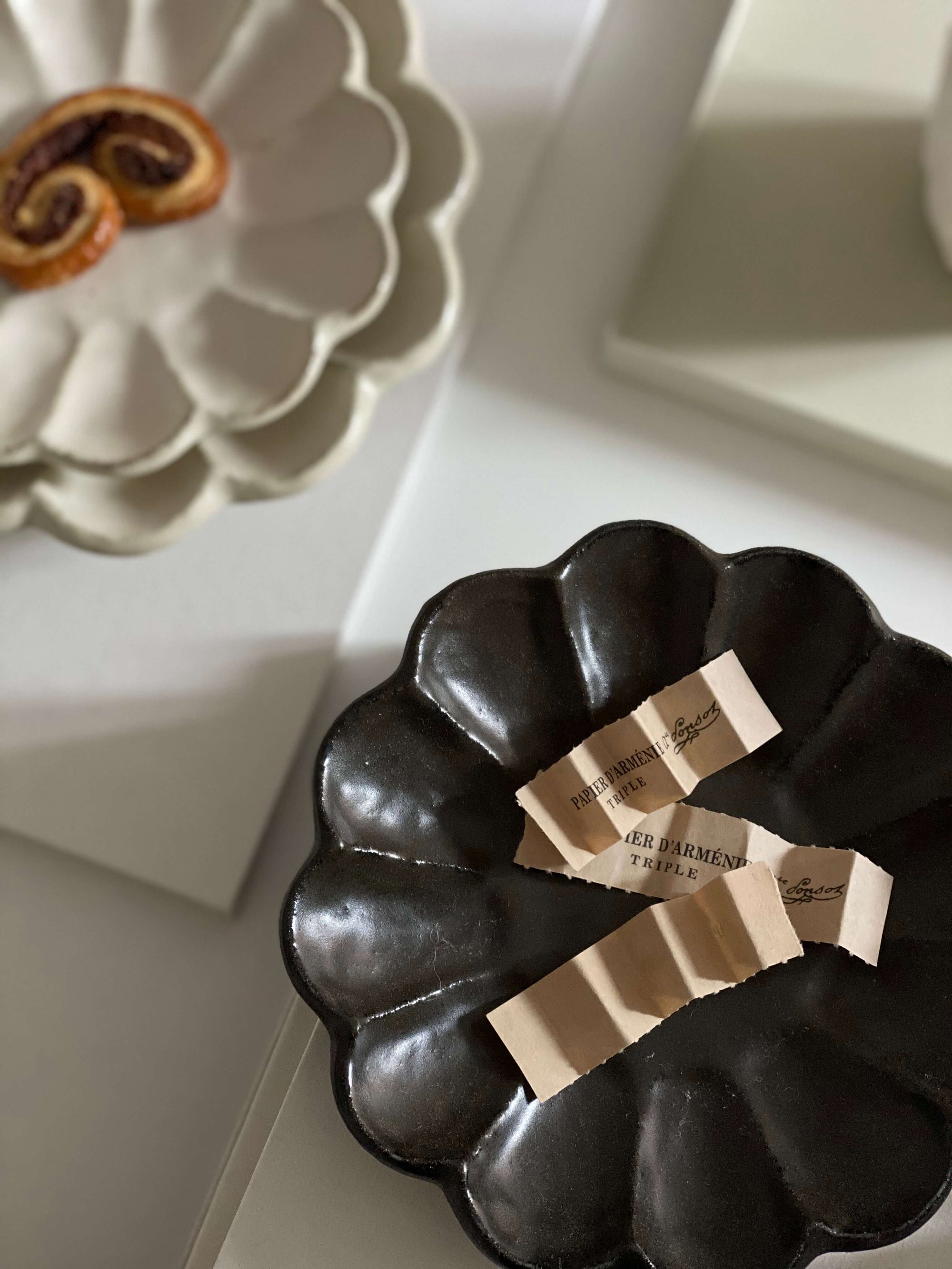 Elegant black and white scalloped plates with tea packets, showcasing modern tableware design.
