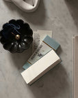 Elegant incense burning in a black dish beside Atelier de Balthus perfume packaging on a marble surface.
