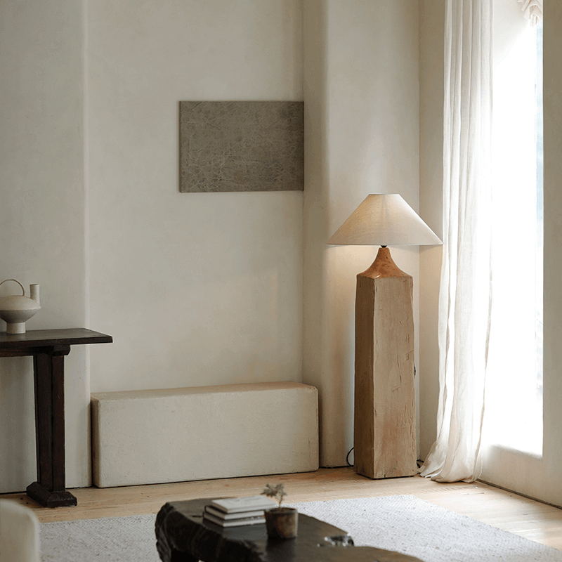 Modern living room with a Stake Floor Lamp featuring linen shade and natural wood base, providing soft, cozy lighting near a large window.