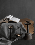 Antique Aimu table candle holder set with distressed details, displayed beside an open book on a rustic wooden box.