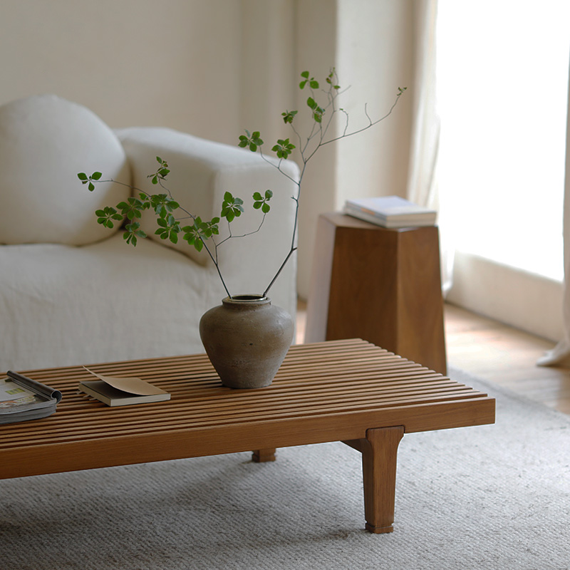 Wooden fence coffee table with a natural finish, holding a vase with greenery, placed in a cozy living room setting.