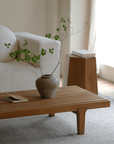 Wooden fence coffee table with a natural finish, holding a vase with greenery, placed in a cozy living room setting.