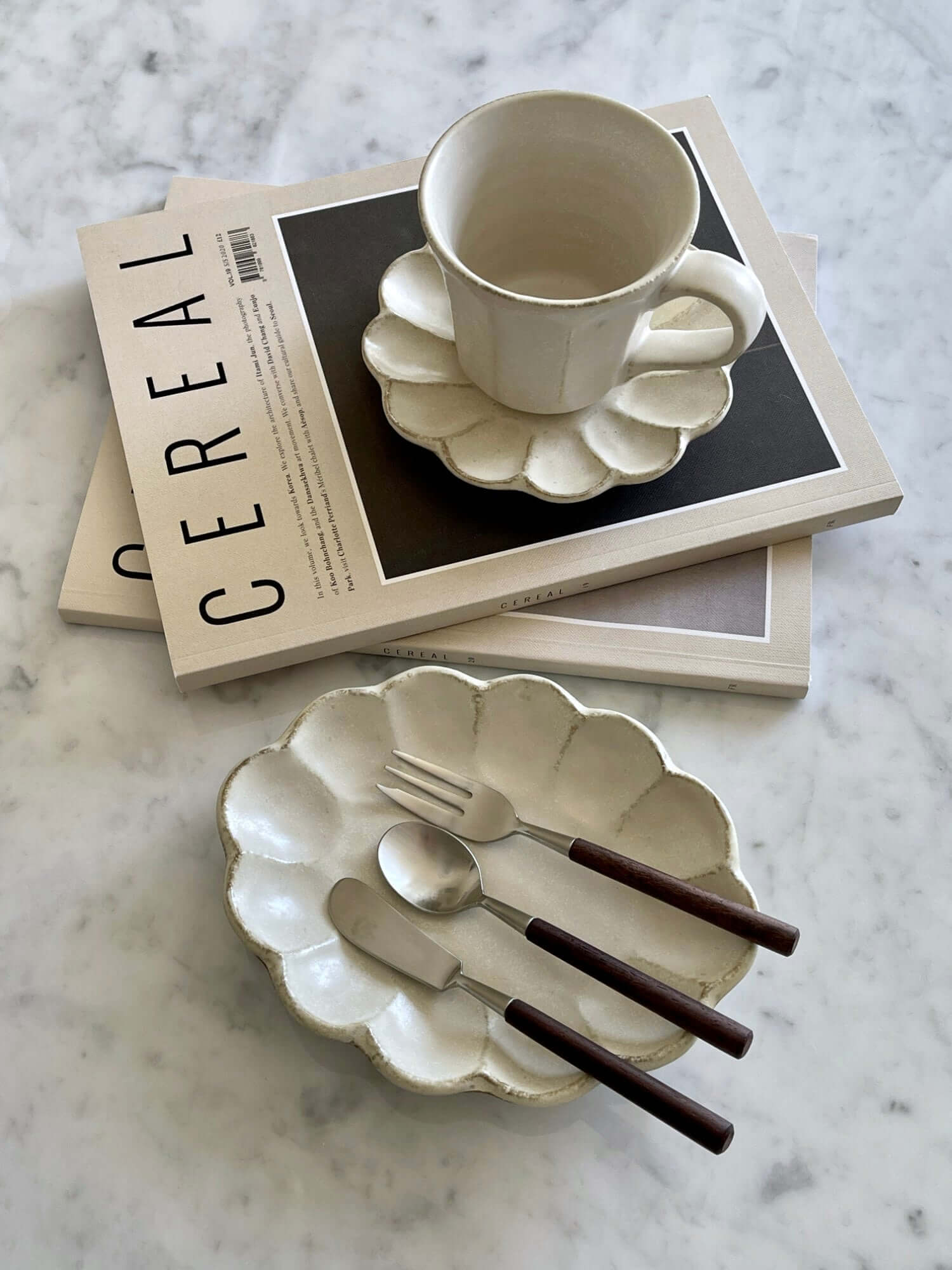 Elegant Rosewood cutlery set with ceramic plate and cup on a marble table.