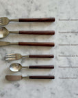 Elegant rosewood cutlery set including dessert fork, dessert spoon, dessert knife, cake fork, teaspoon, and butter knife on marble背景