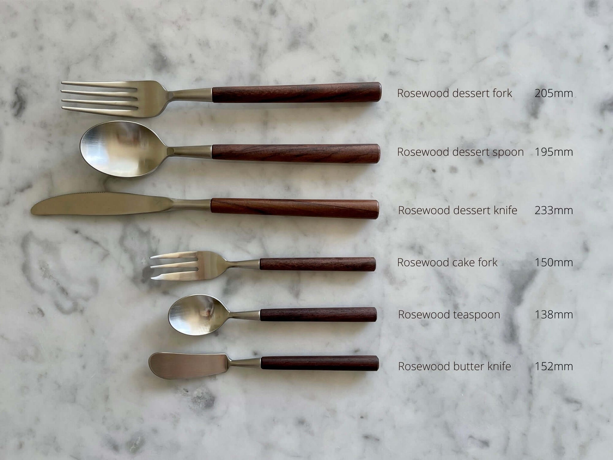 Elegant rosewood cutlery set including dessert fork, dessert spoon, dessert knife, cake fork, teaspoon, and butter knife on marble背景