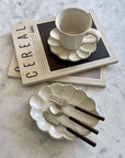 Elegant Rosewood cutlery set with ceramic plate and cup on a marble table.