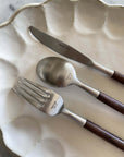Elegant Rosewood cutlery set on white plate, featuring a knife, fork, and spoon with unique wooden handles.