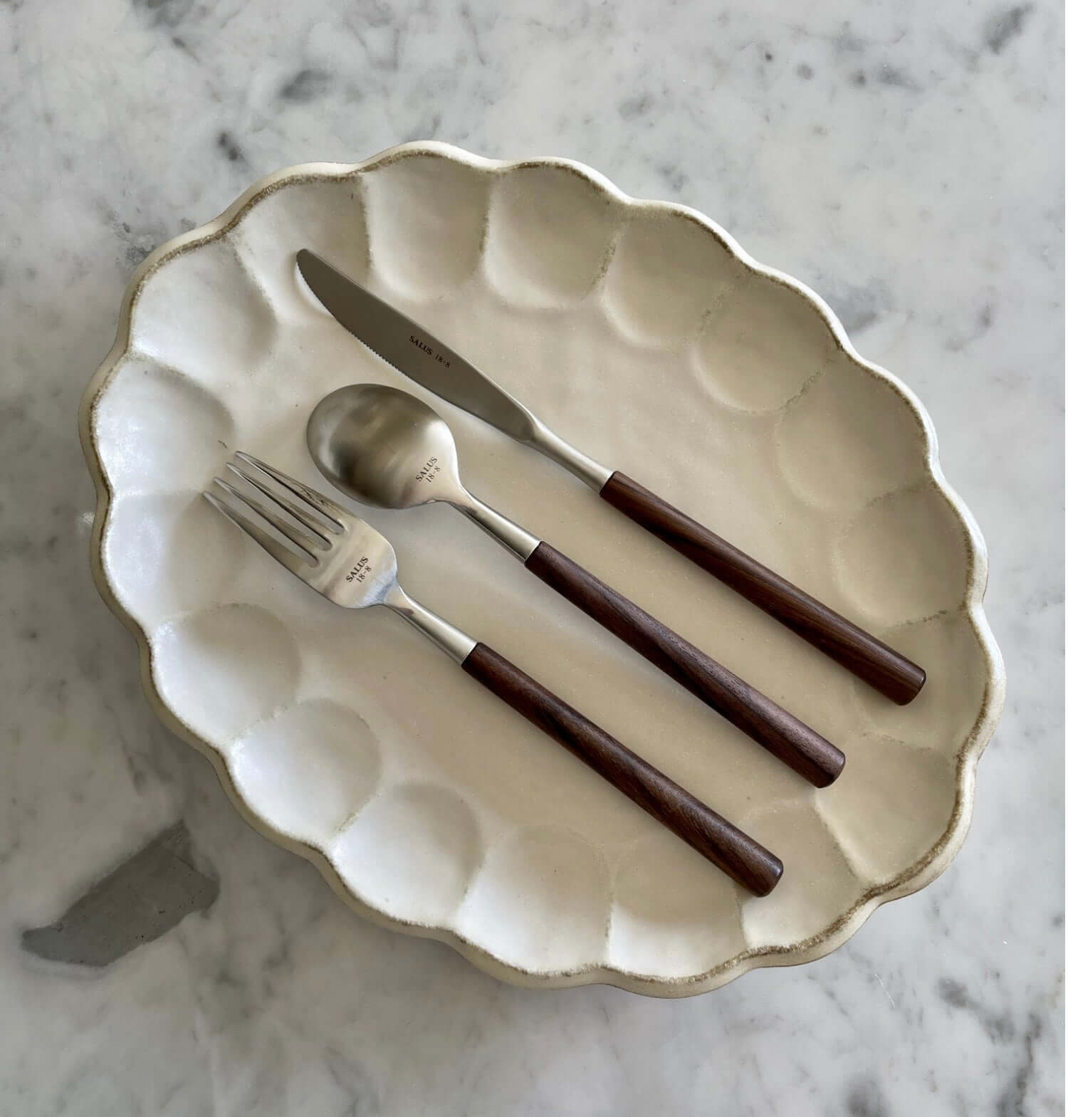 Elegant rosewood cutlery set with natural wood handles on a decorative plate, showcasing unique color and elegant design.