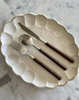 Elegant rosewood cutlery set with natural wood handles on a decorative plate, showcasing unique color and elegant design.