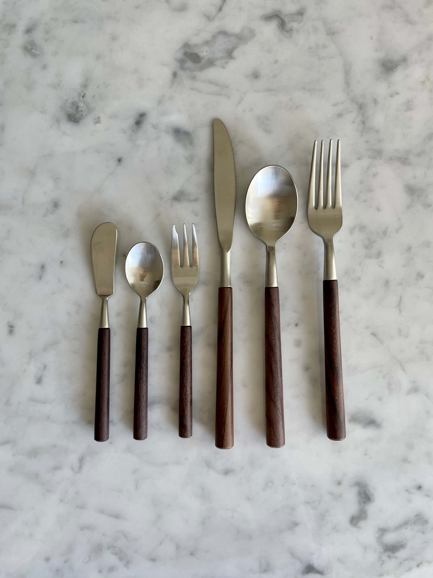 Elegant Rosewood cutlery set with unique natural wood handles displayed on a marble surface.