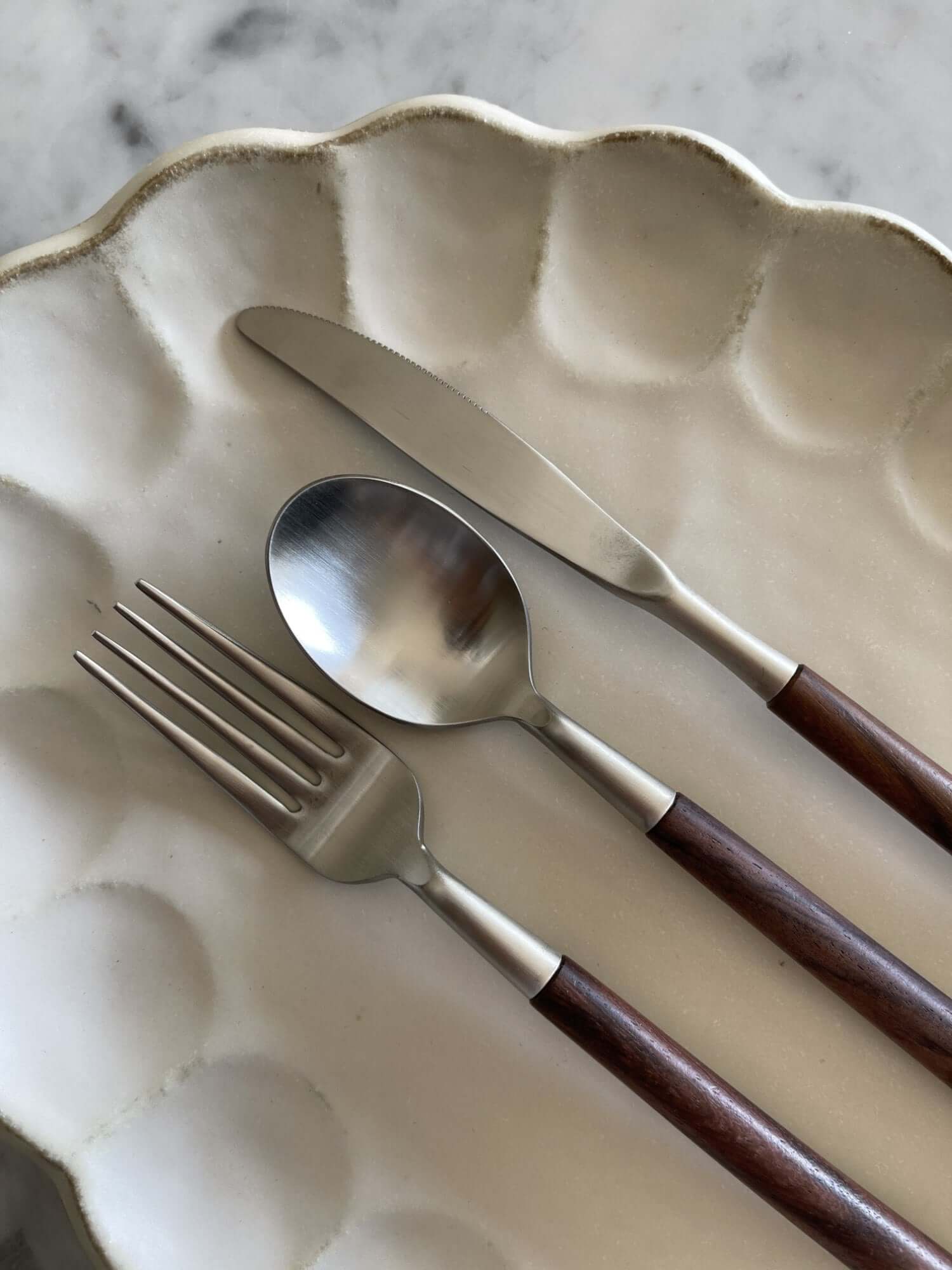 Elegant rosewood cutlery set with unique handles on a decorative plate.