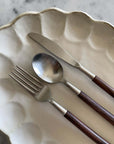 Elegant rosewood cutlery set with unique handles on a decorative plate.