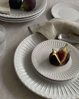 Elegant porcelain plates with soft lace edges and figs, evoking nostalgia and sophistication, perfect for fine dining.
