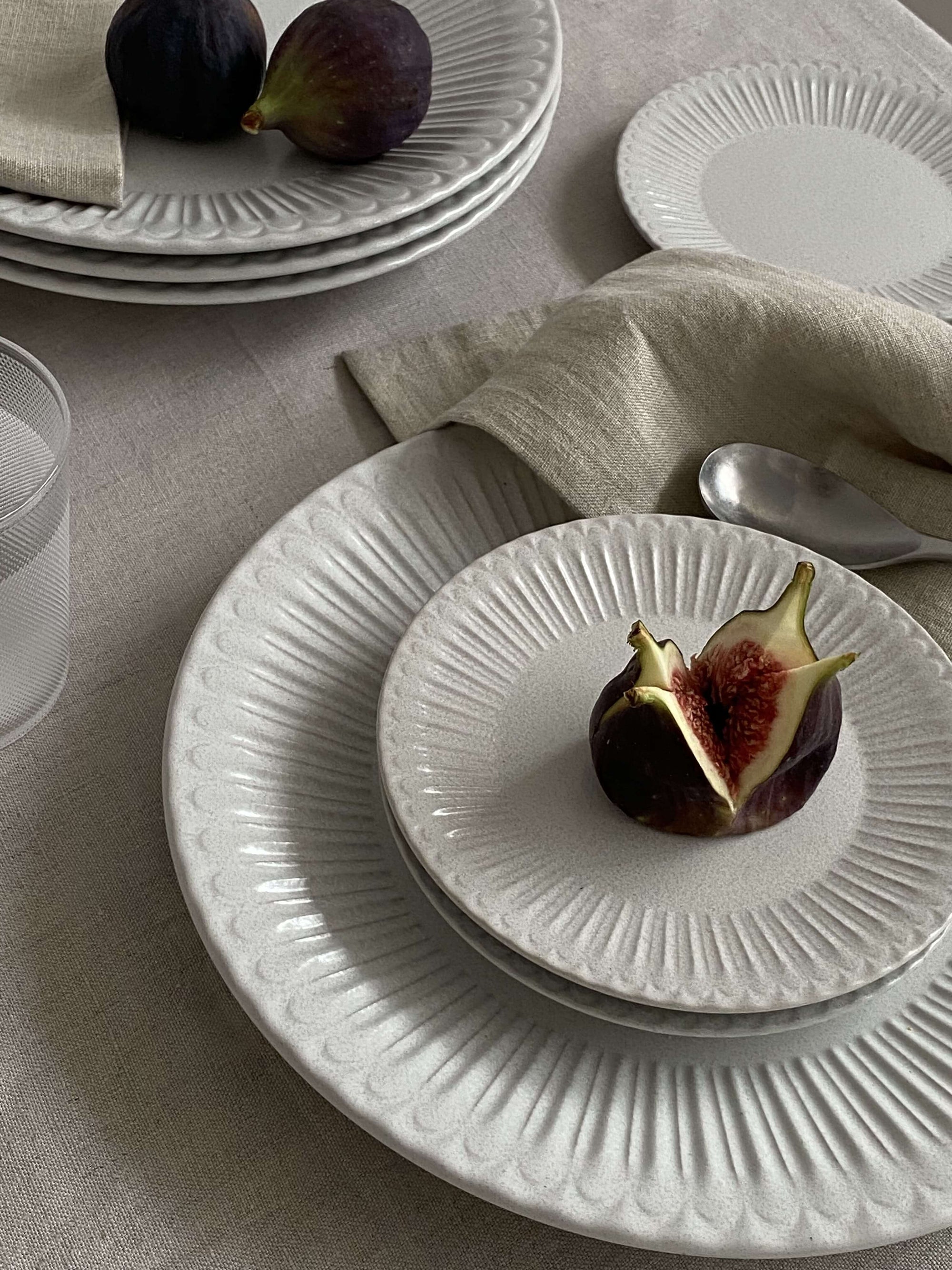 Elegant porcelain plates with fig on table, featuring soft lace design and antique-style finish, evoking nostalgia and romance.
