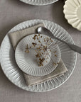 Elegant porcelain plates with soft lace edges and flecked finish, showcasing sophisticated tableware for nostalgic dining.