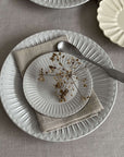 Elegant porcelain plates with soft lace edges and flecked finish, showcasing sophisticated tableware for nostalgic dining.