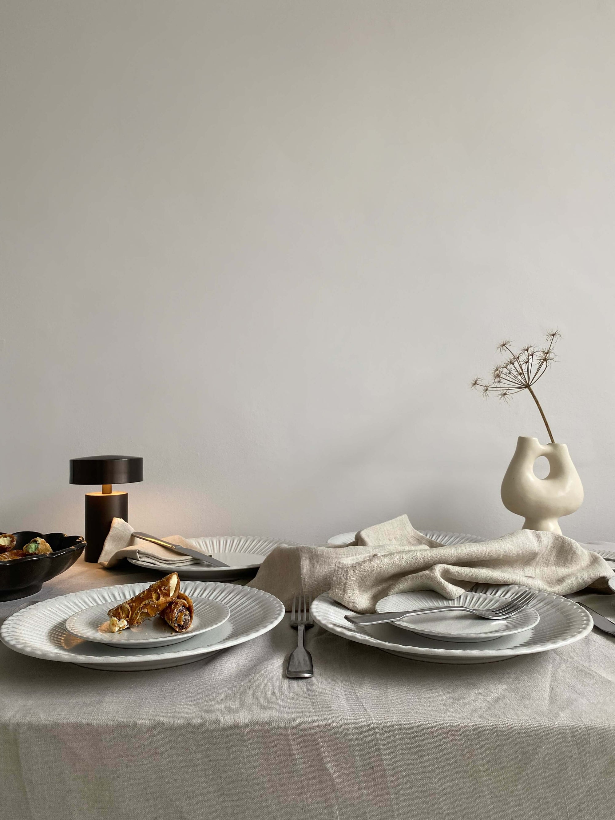 Elegant dining table set with white porcelain plates, soft lace edges, and decorative elements evoking nostalgia and sophistication.